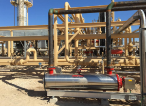 A silver tank sits on an outdoor piping system on a sunny day.